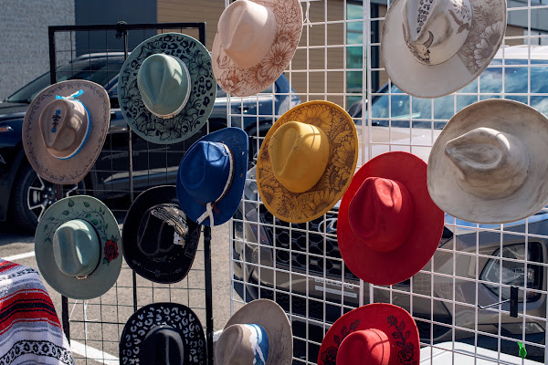 Un présentoir de chapeaux western roses, rouges, jaunes, verts et bleus