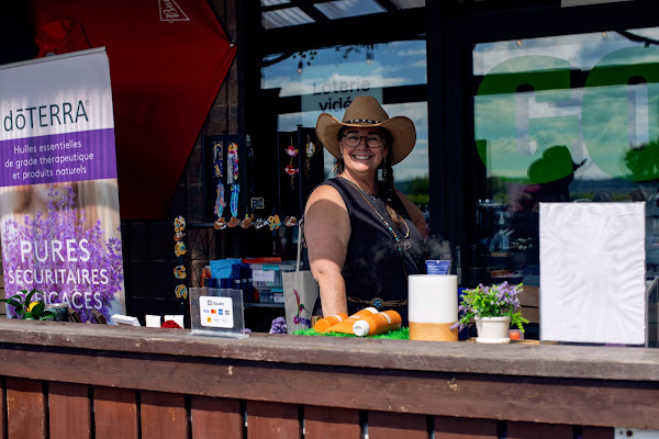 Une exposante souriante en chapeau western derrière son kiosque